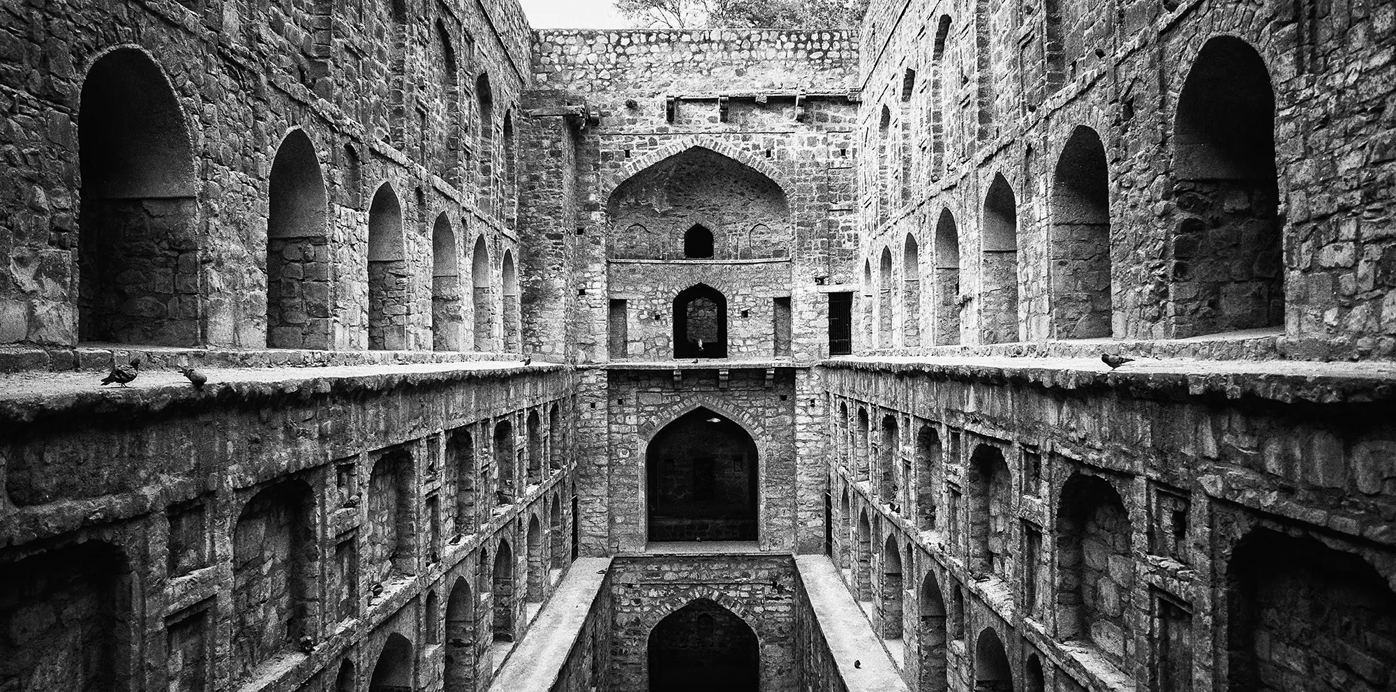 The arched niches and stone steps of Agrasen ki Baoli descending in symmetrical tiers.