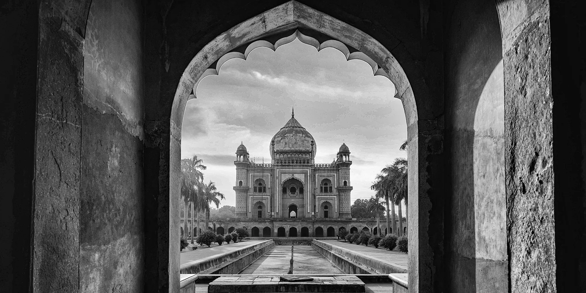 Safdarjung’s Tomb framed through the scalloped arch of its gateway, the water channel leading to the mausoleum.